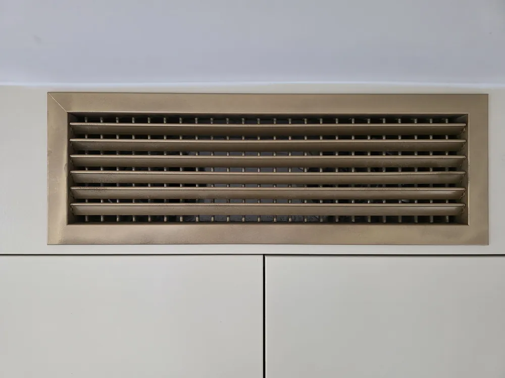 Brass air grille set into the wardrobe cornice