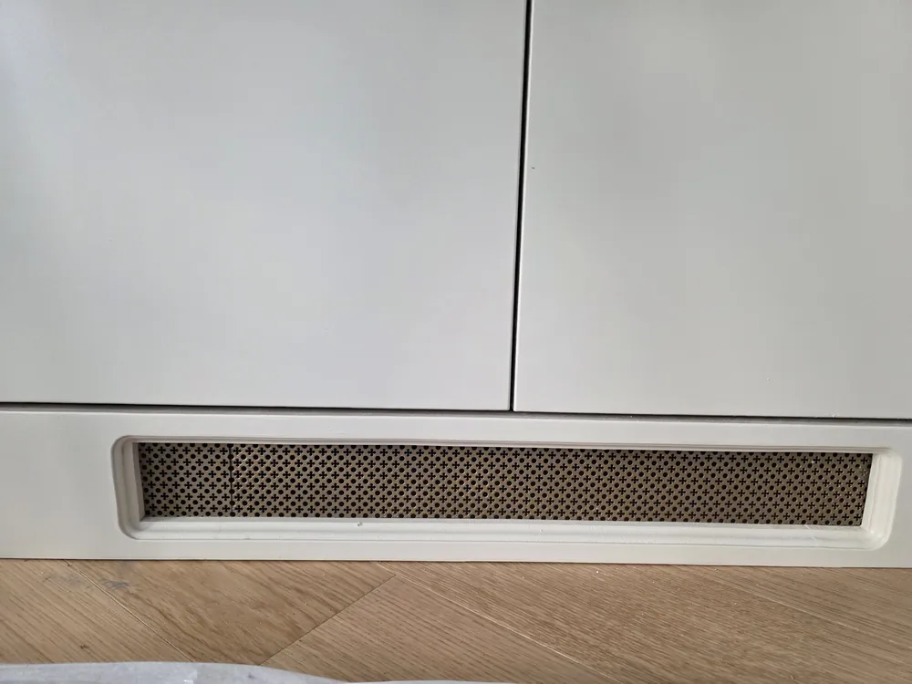Painted plinth with a perforated brass vent under the doors